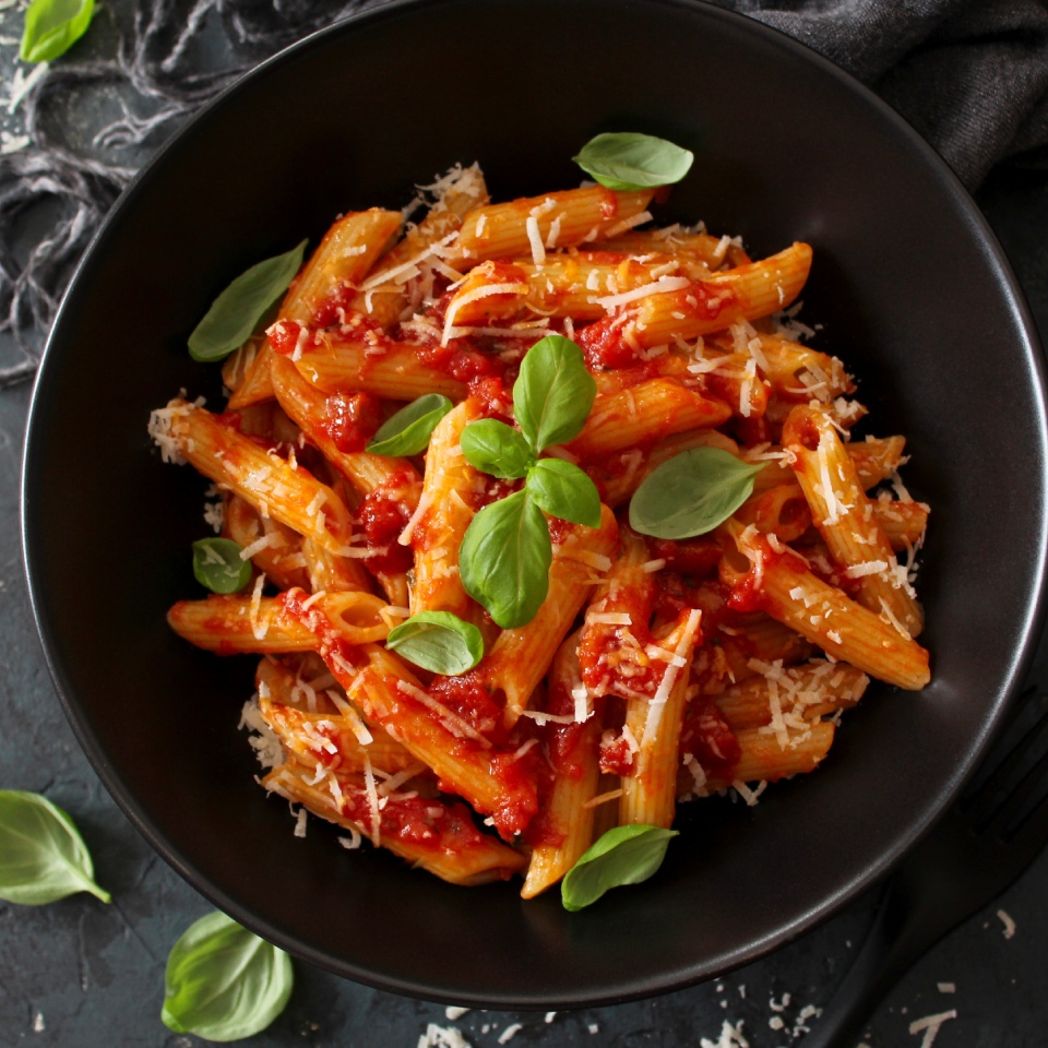 Plato de macarrones con tomate, queso rallado y albahaca